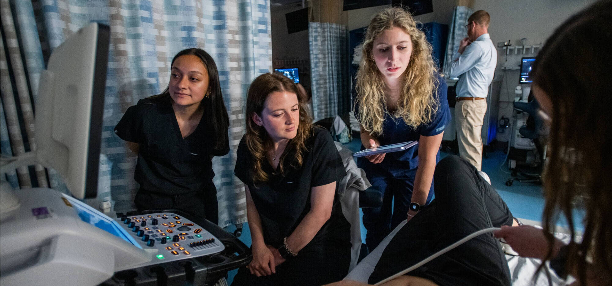 Sonography students gather around to observe sonography demonstration